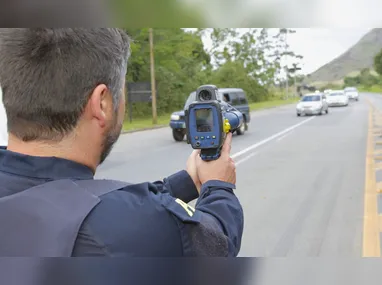 Policial rodoviário fiscaliza condutores em rodovias, com auxílio de um radar móvel