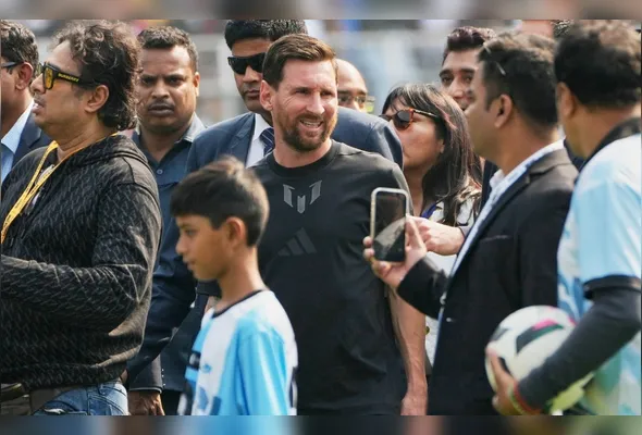 O astro do futebol argentino Lionel Messi caminha com um menino ao chegar ao Estádio Salt Lake, em Calcutá, na Índia, neste sábado, 13 de dezembro de 2025