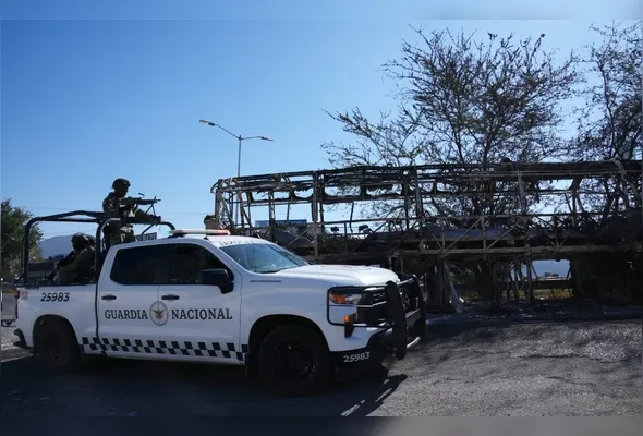 Agentes da Guarda Nacional do México fazem patrulha onde um ônibus incendiado bloqueava pistas de uma rodovia em Guadalajara, no México, nesta segunda-feira (23), em meio à onda de violência desencadeada no país após a morte do narcotraficante El Mencho