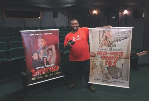 Leandro Sherman, no cinema do Sesc Glória, com cartaz dos seus filmes