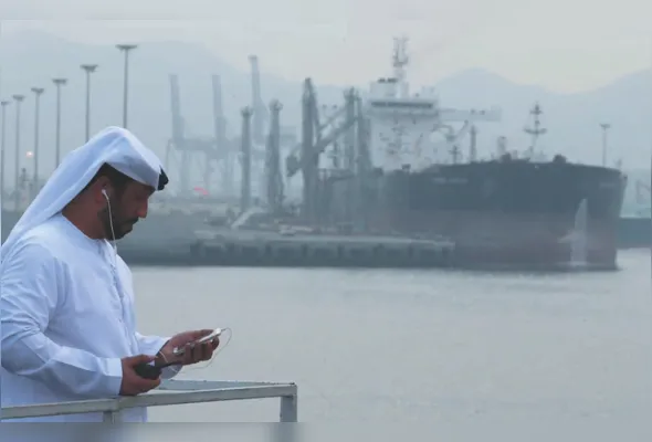 Operador emiradense em porto na cidade de Fujairah com navio petroleiro ao fundo: 8º maior produtor