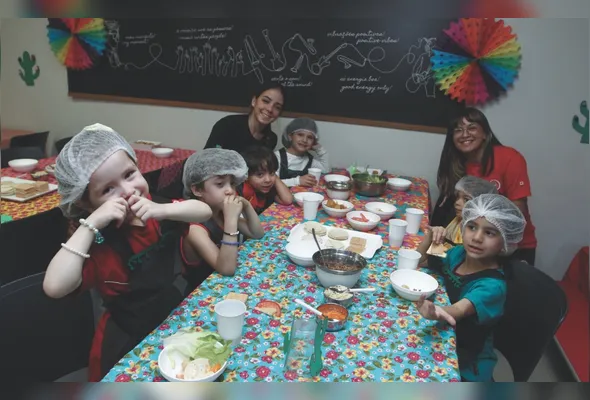 Rebeca e Laysla acompanham crianças durante atividade na hora do lanche, na colônia de férias da Maple Bear