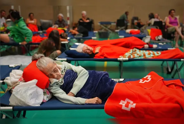 Moradores passam a noite em um centro esportivo após serem retirados de suas casas devido à ameaça de um incêndio florestal em Cebreros, na província de Ávila, região de Castela e Leão, nesta sexta-feira (24)