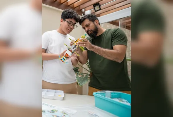 Professor e aluno trabalham juntos em atividade de robótica com a metodologia ETC da Microkids, que integra tecnologia e desenvolvimento humano no ensino.