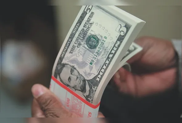 Notas de dólar, que caiu em relação ao real e fechou a R$ 5,008, devido à percepção de menor impacto