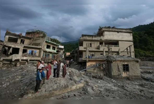 Residentes observam estruturas danificadas após enxurrada atingir a região de Devighat, no distrito de Nuwakot, no Nepal