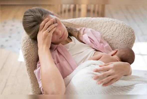 Mãe amamenta filho enquanto demonstra sinais de exaustão: entre 50% e 80% das puérperas podem sofrer de baby blues