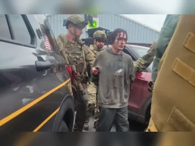 Dezenas de agentes -vestindo trajes militares e armas- posaram para uma foto ao redor do preso