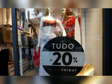 Consumidora observa a propaganda da Black Friday na vitrine de loja
