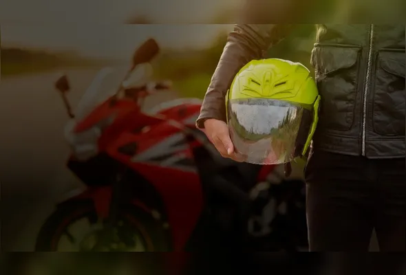 Motociclista segura capacete ao lado de moto; taxa de fatalidade sem o equipamento é seis vezes maior, segundo a OMS