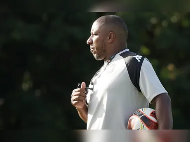 Criança é levantada por um adulto para conseguir fazer uma cesta