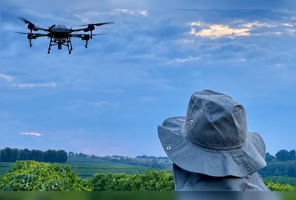 Trabalhador com drone em plantação de café: oferta de formação profissional rural e capacitação de empregados para o agronegócio