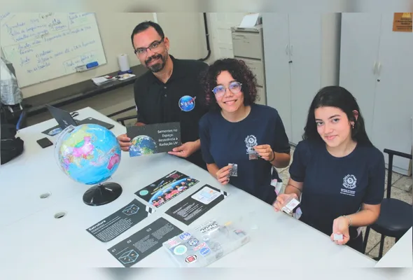 Luiz Gustavo Gomes, professor orientador, destaca a proteção das sementes contra a radiação; as estudantes Thainara Alves da Cruz, 16, e Ana Clara Rezende, 17, contam sobre o interesse pela pesquisa científica e a experiência de participar do projeto