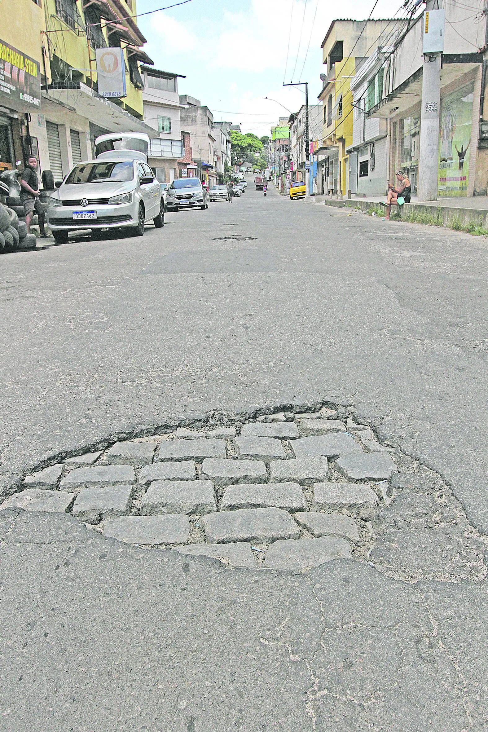 Rua Presidente Getúlio Vargas tem falha no asfalto, com blocos à mostra.