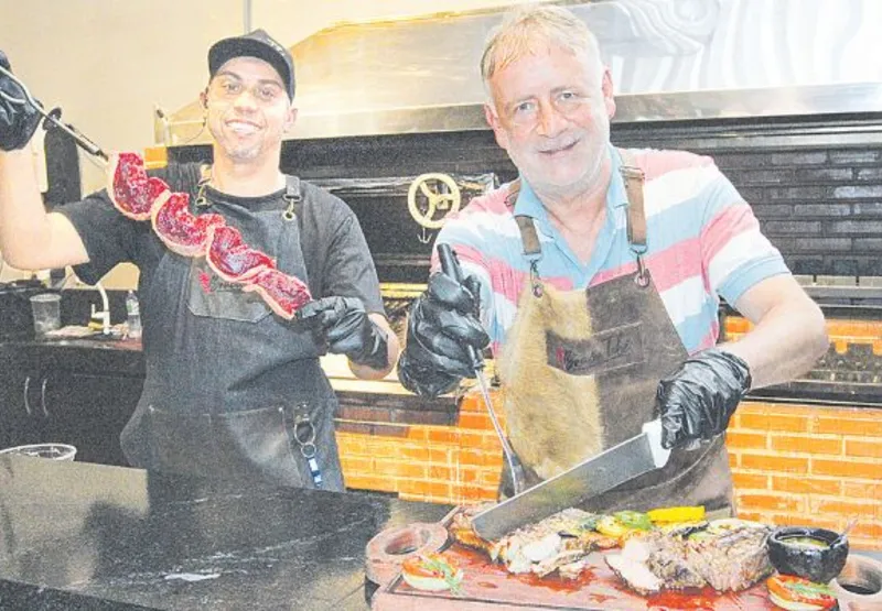 O churrasqueiro Geovane Luiz e o empresário Gilmar Scherer espetam a carne crua, sem sal, e depois temperam.
