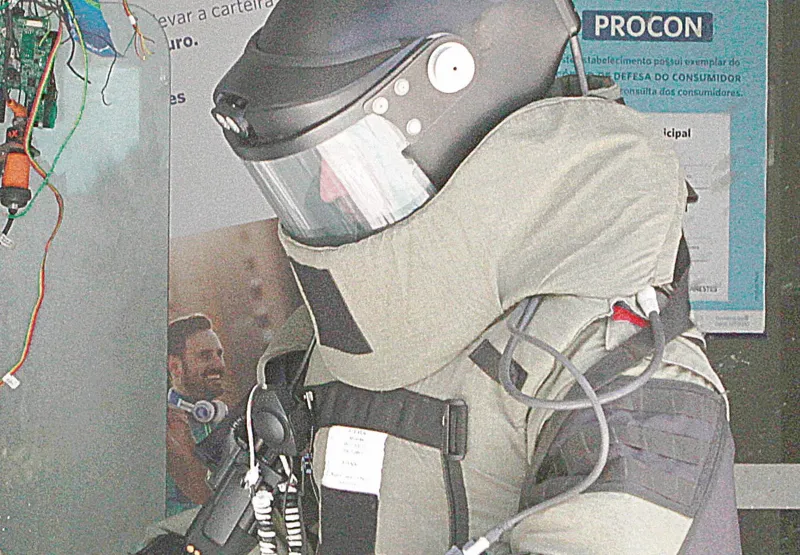 Policial da equipe antibombas recolhe material  após ataque de quadrilha
