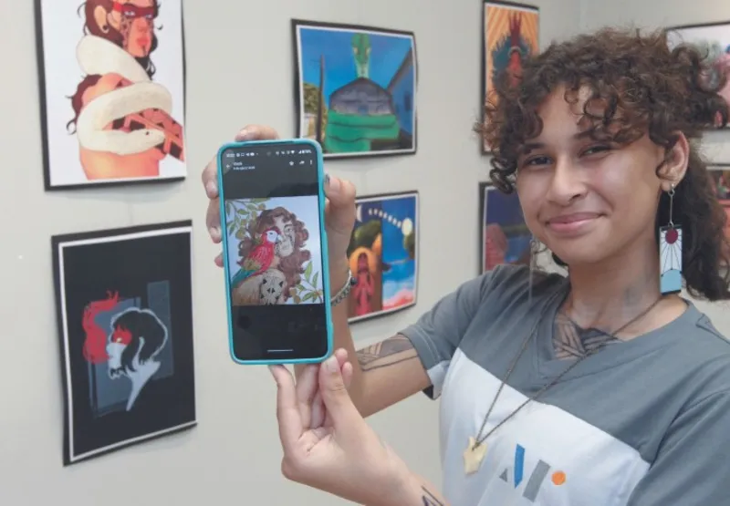 Luiza Marques Santiago mostra, na tela do celular, obra que foi  exposta no ArtCom Expo International