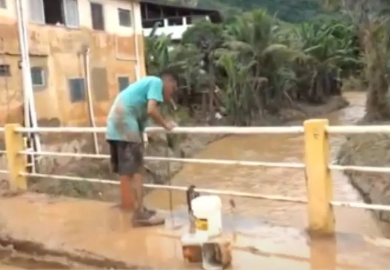 Morador utiliza água do rio para tentar limpar loja em Mimoso do Sul