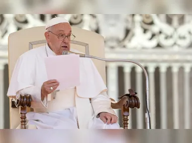 Mulher deixa rosário perto de velas com a foto do papa Francisco do lado de fora do Hospital Policlínico Universitário Agostino Gemelli, em Roma, na Itália, onde o pontífice segue internado