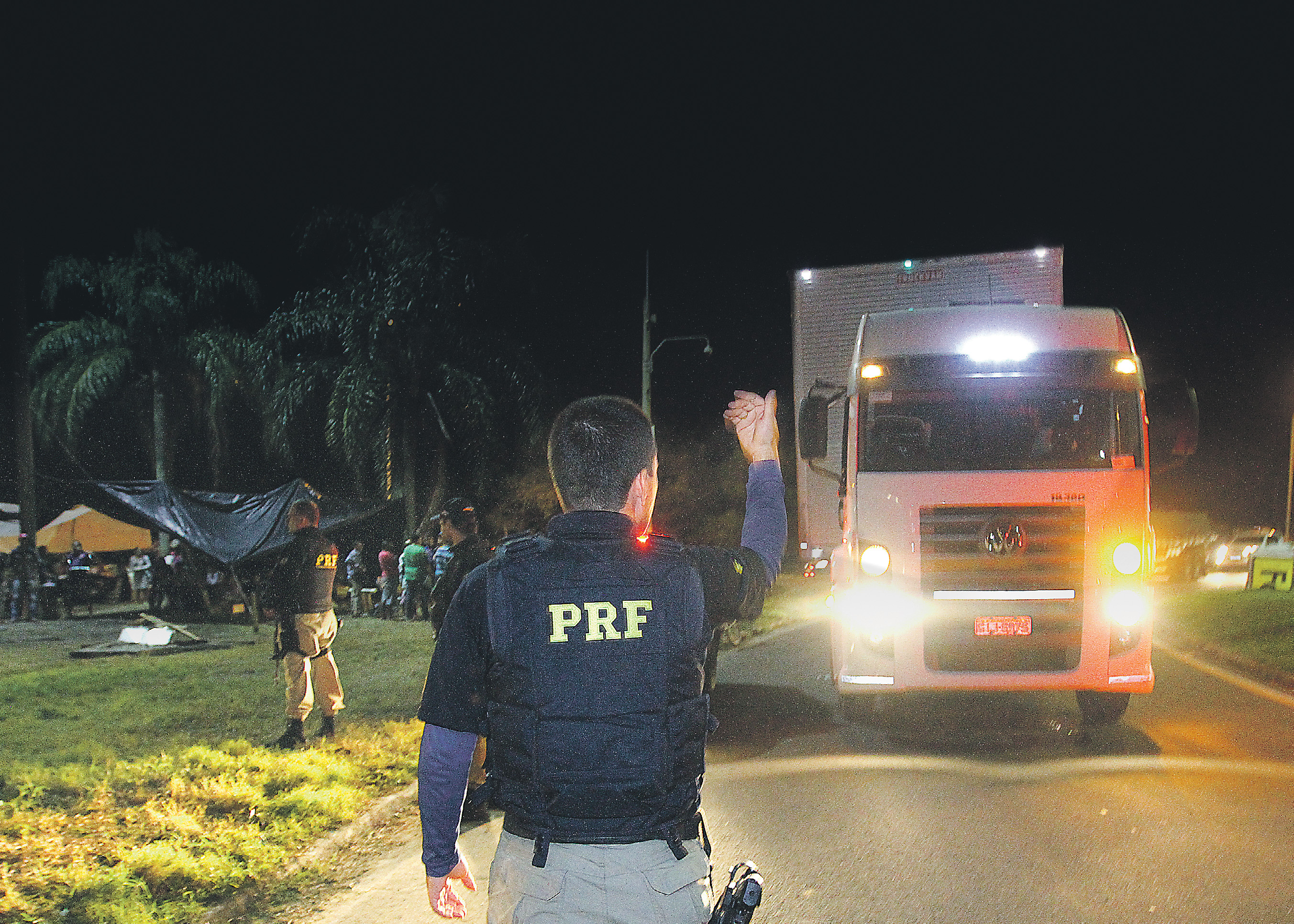 Policial rodoviário federal sinaliza para motorista seguir caminho, após liberar o trânsito na BR-101, em Viana. (Foto: Dayana Souza)