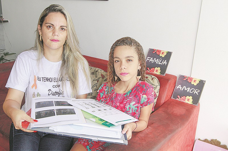 Letícia Barbosa e a filha Júlia mostram exames que precisaram fazer até conseguir o diagnóstico da doença (Foto: Kadidja Fernandes/at)