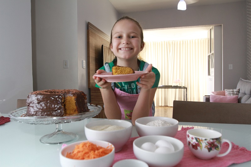 Pérola Zache, de 9 anos, exibe com orgulho o bolo de cenoura com chocolate feito por ela (Foto: Dayana Souza/ AT/ 04/12/2018)