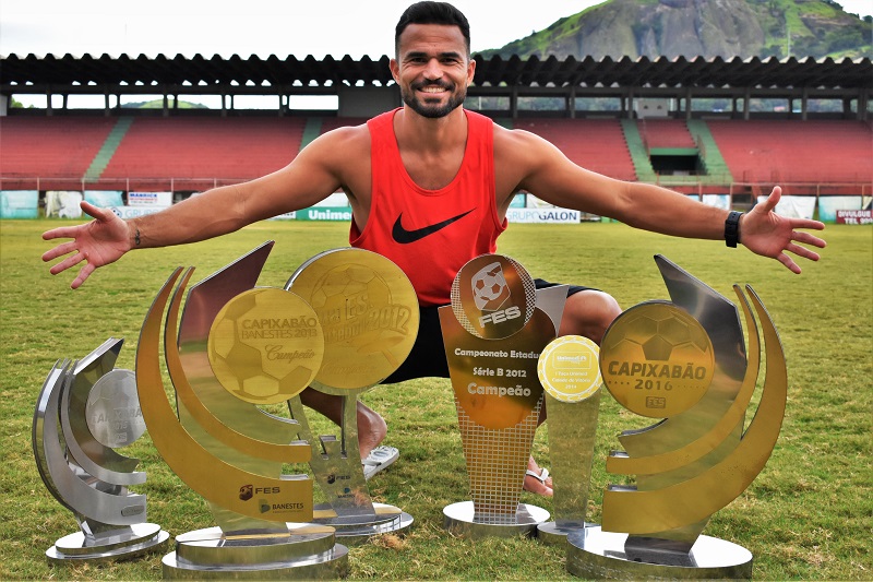 O goleiro Felipe posa, no gramado do estádio Engenheiro Araripe, com os principais troféus conquistados nos sete anos em que vestiu a camisa 1 da Desportiva (Foto: João Brito/ Desportiva)
