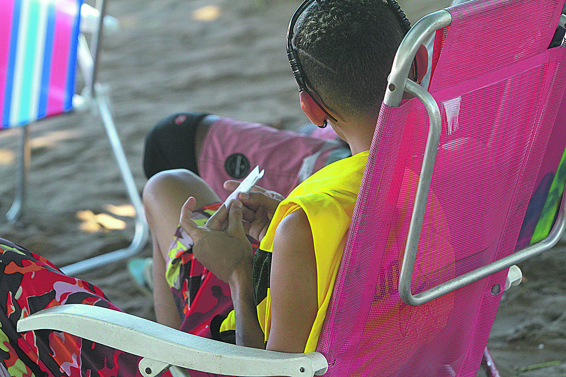 Jovem prepara cigarro de maconha e fuma próximo de outros banhistas na Ilha do Boi, em Vitória. (Foto: Dayana Souza/AT)