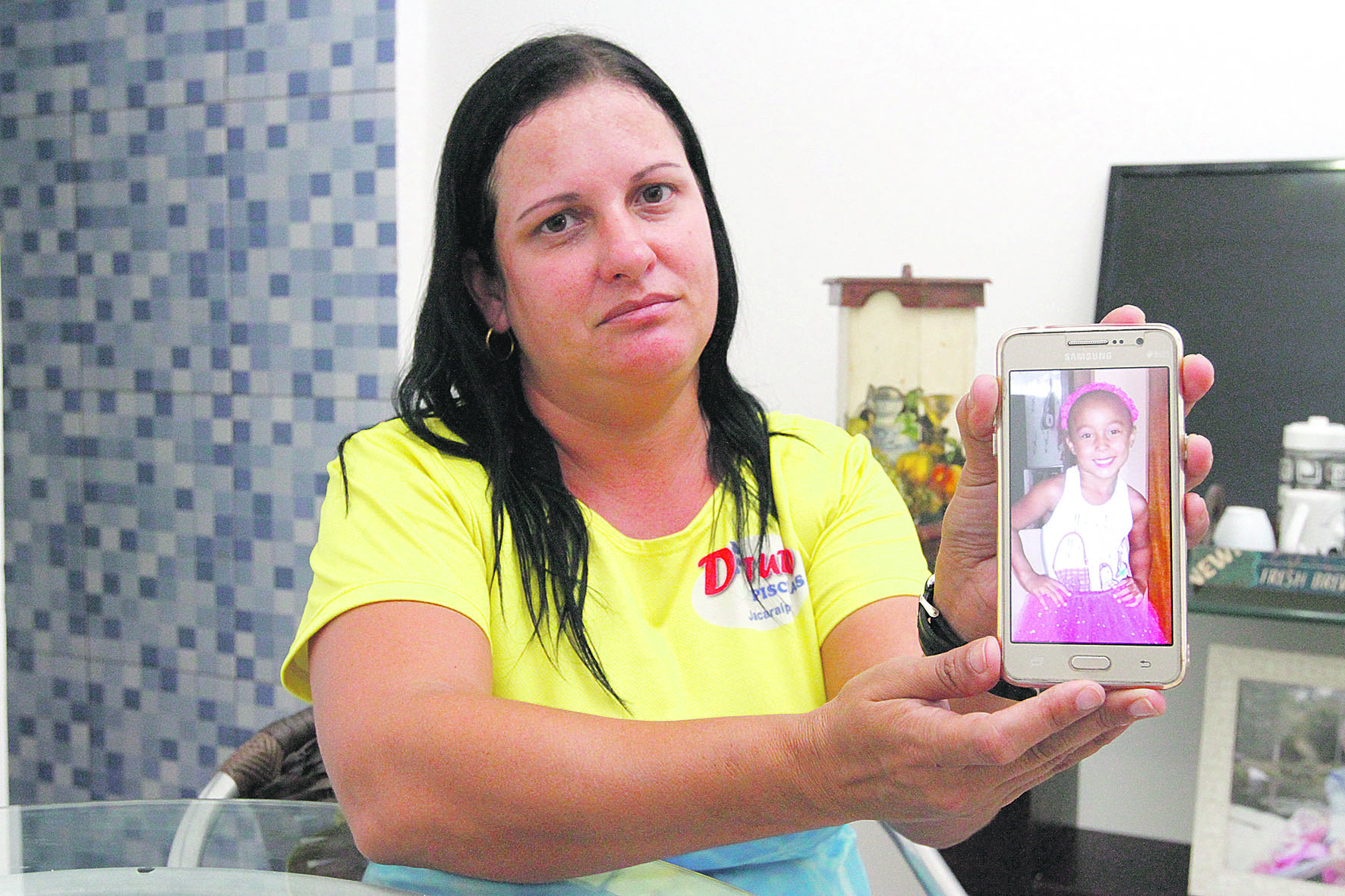 Clarice de Oliveira mostra no celular a foto da filha Isadora, que pode ter morrido de dengue hemorrágica. (Foto: Leone Iglesias/ AT)