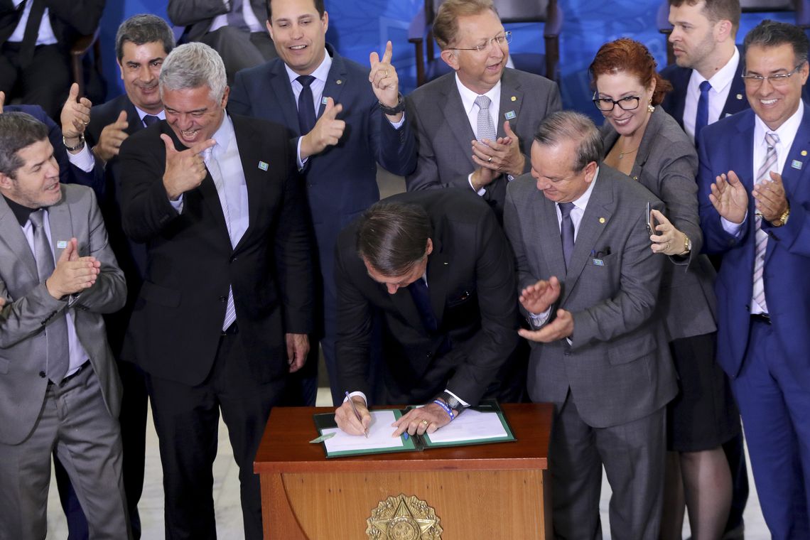 O presidente da República, Jair Bolsonaro, assina o decreto que dispõe sobre a aquisição, o cadastro, o registro, a posse, o porte e a comercialização de armas - SINARM e SIGMA. (Foto: Wilson Dias/Agência Brasil)
