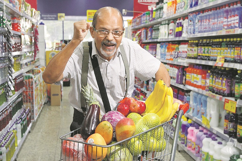 O aposentado Luiz Carlos, de 71 anos, comemora o prêmio em supermercado, com o carrinho de compras cheio (Foto: Leone Iglesias/AT)