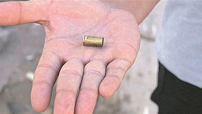Morador com cápsula de pistola, encontrada no local (Foto: Reprodução/Imagens TV Tribuna)