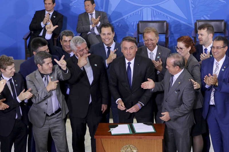 Jair Bolsonaro cercado por parlamentares durante assinatura de decreto que flexibiliza porte, posse e comercialização de armas (Foto: Wilson Dias/ Agência Brasil )