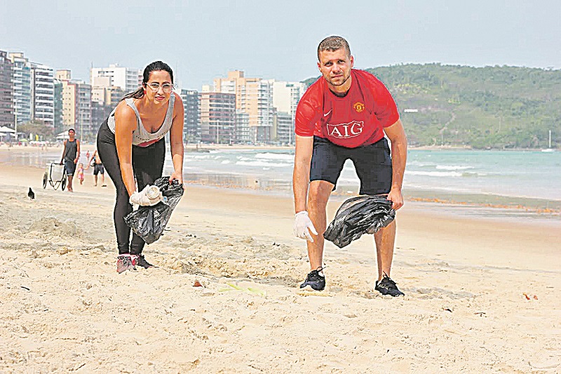 Carina Cristóvão e Diogo Gama recolhem lixo na Praia do Morro durante atividade física: consciência ecológica (Foto: Roberta Bourguignon)