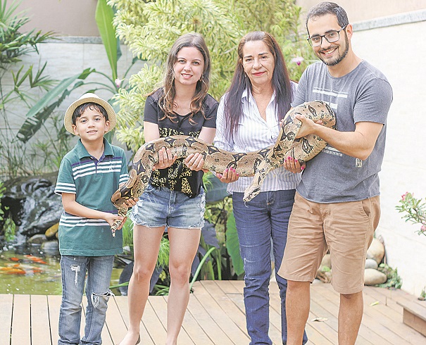 Gilmar, Joyce, Maria e Thiago seguram a jiboia que é chamada de Sabrina, tem 1,45m e pesa 13 quilos (Foto: Roberta Bourguignon/AT)