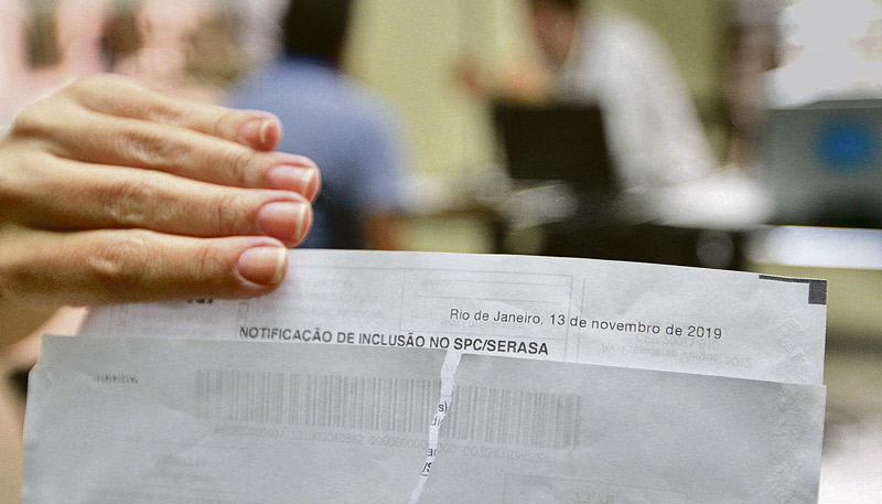 Designer de interiores, de 50 anos, monstra uma notificação indevida de débito (Foto: Leone Iglesias / AT)