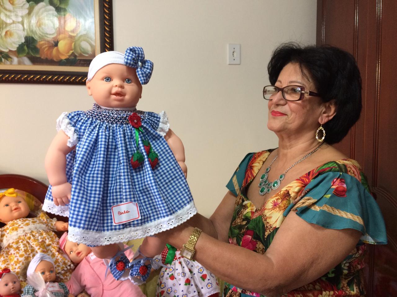 Chiquita mostra uma das bonecas que restaurou e que será doada no Natal. (Foto: Reprodução)