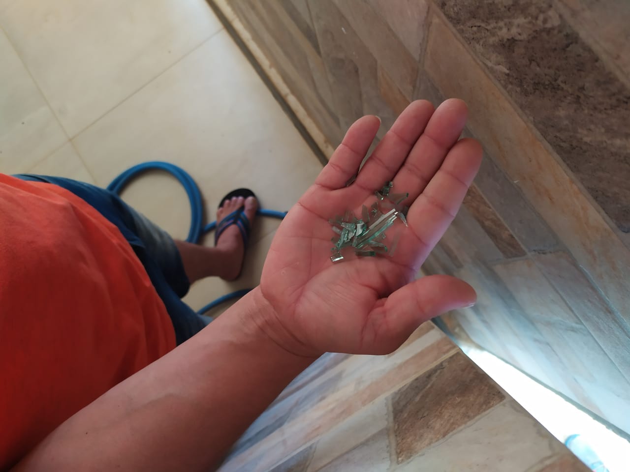 Policial mostra os estilhaços de vidro da janela atingida (Foto: Júlia Afonso)