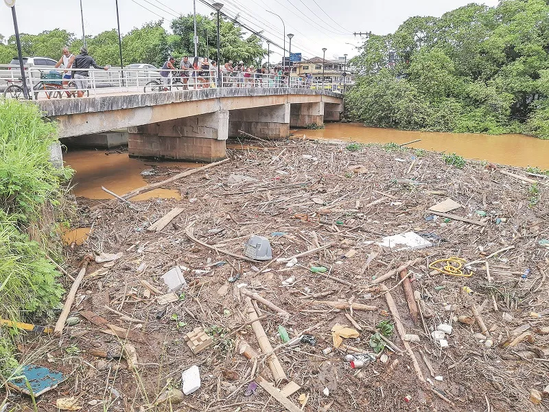 Moradores e turistas observam da ponte o lixo que chega às praias de Piúma através do Rio Novo