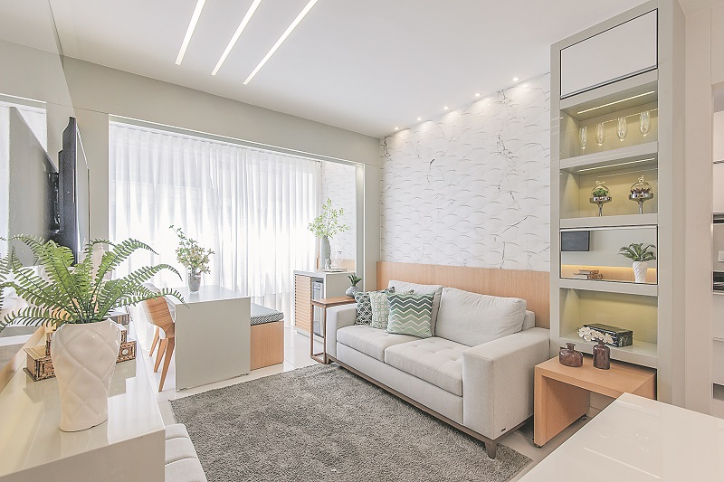 Sala do apartamento decorado do Edifício Pienza, em Vila Velha: cores neutras e móveis versáteis foram usados pela arquiteta Karol Simonasse para organizar e aproveitar melhor o espaço do imóvel de dois quartos, como a mesinha rodízio que fica embaixoda cristaleira (Foto: Giovanna Gonçalves/Grand Construtora)