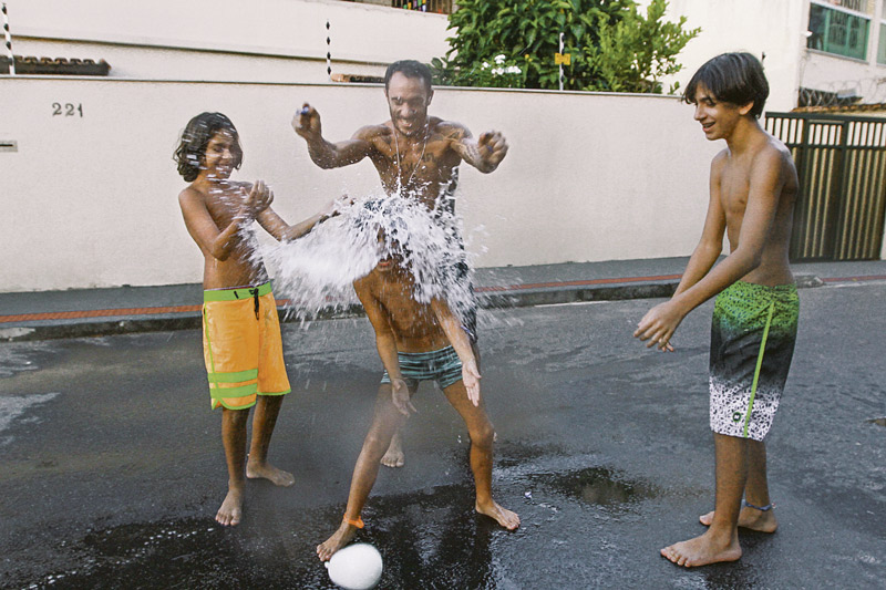 Igor Moura e os filhos Yann, Theo e Davi brincam de “guerra de bexigas d'água”. O pai afirma que a brincadeira é uma forma de juntar toda a família em momentos de lazer e alegria (Foto: Leone Iglesias / AT)