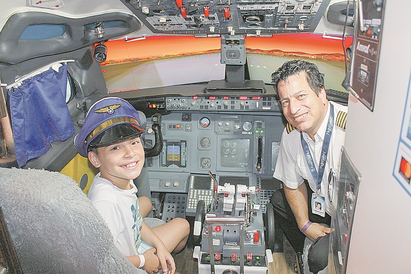 O estudante Kaiky Pereira, de 9 anos, ao lado do comandante de avião Valmir Freitas, conheceu o simulador de voo (Foto: Julio Huber)
