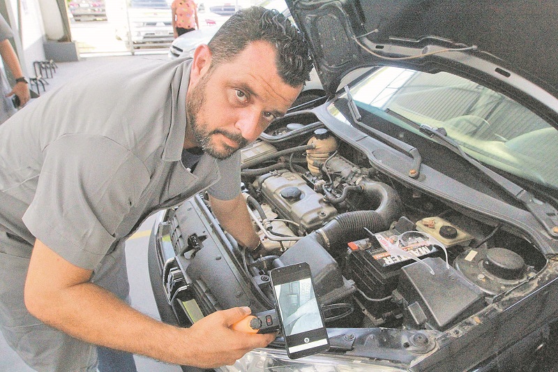O perito Wagner Limeira usa celular para fotos ao fazer demonstração de como será o novo tipo de vistoria em veículo (Foto: Leone Iglesias/AT)