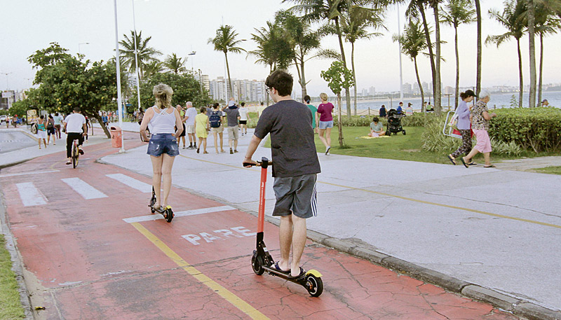 Usuários com patinete no calçadão da Praia de Camburi, em Vitória (Foto: Dayana Souza / AT)