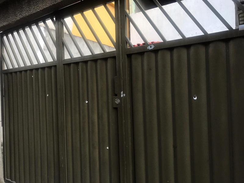 Marcas de tiros no portão da casa onde moram idosa e neto. (Foto: Bruna Maria)
