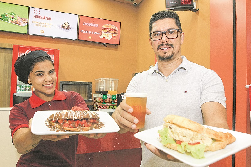 Pablo Vitorazzi, ao lado da atendente Jheniffer Souza, está oferecendo um chope Heineken de 300 ml para quem pedir um croassonho grande, salgado ou doce (Foto: Dayana Souza/AT)