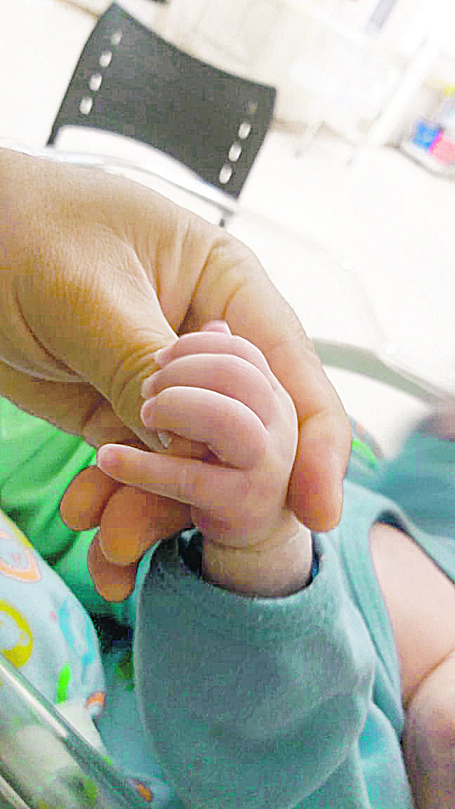 Pai segura a mão do bebê de cinco meses que venceu o coronavírus (Foto: Acervo pessoal)