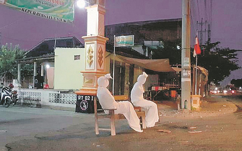 Jovens vestidos de pocong para garantir que a quarentena seja cumprida pelos moradores nos vilarejos (Foto: Divulgação)