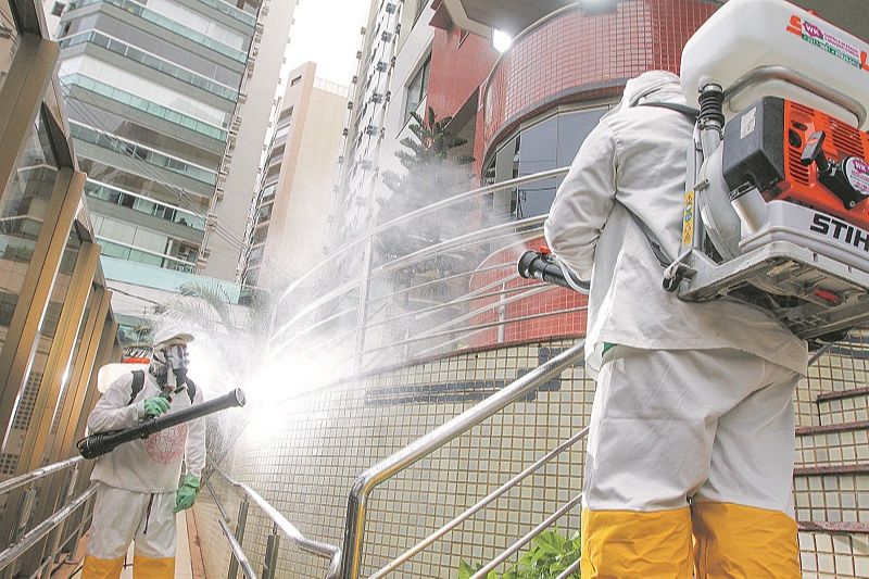Funcionários de empresa fazem desinfecção com aparelhos especiais em áreas comuns de prédio em Vila Velha (Foto: Beto Morais/ AT)