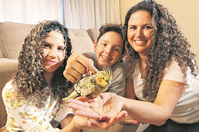 Harrica e os filhos Yasmim e Paulo César se divertem com a calopsita Lilica: “Melhora o nosso humor”, diz a mãe (Foto: Beto Morais/AT)